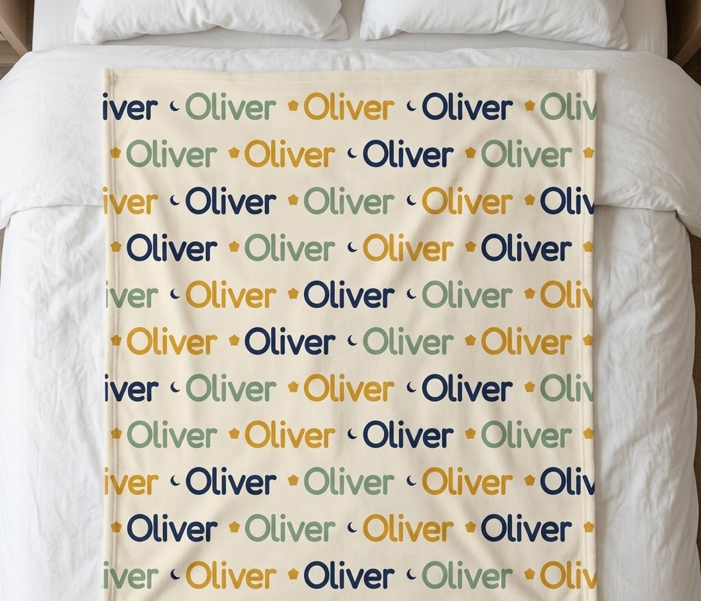 Repeat name blanket with Oliver in navy, sage and mustard, flat on a bed