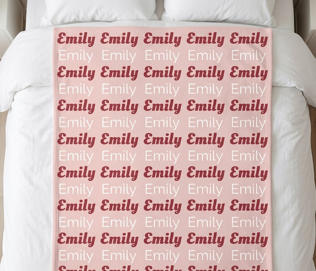 Girl name repeat blanket with Emily in rose and white rows on a bed
