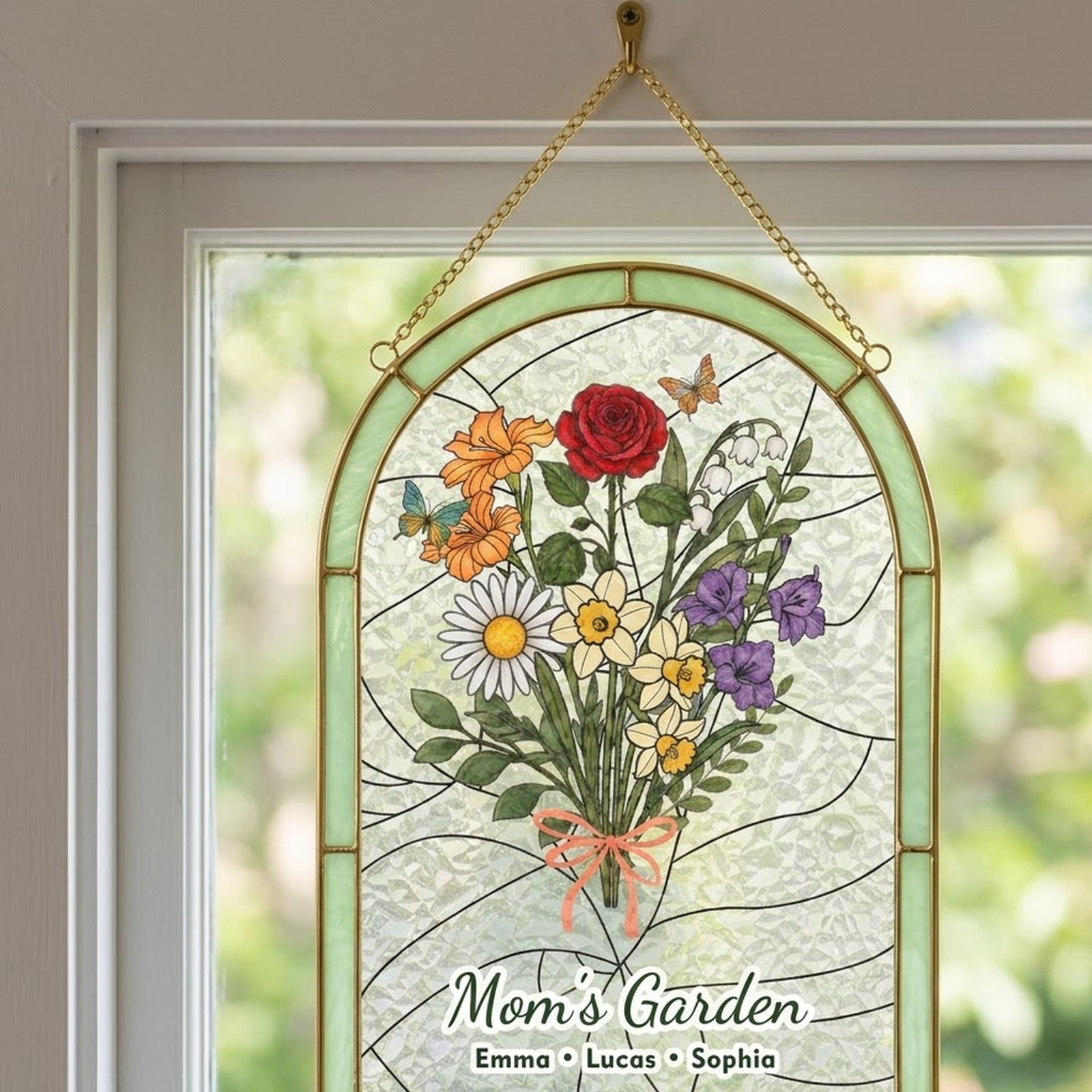 Arched Mom's Garden birth flower suncatcher hanging on a gold chain in a sunny window