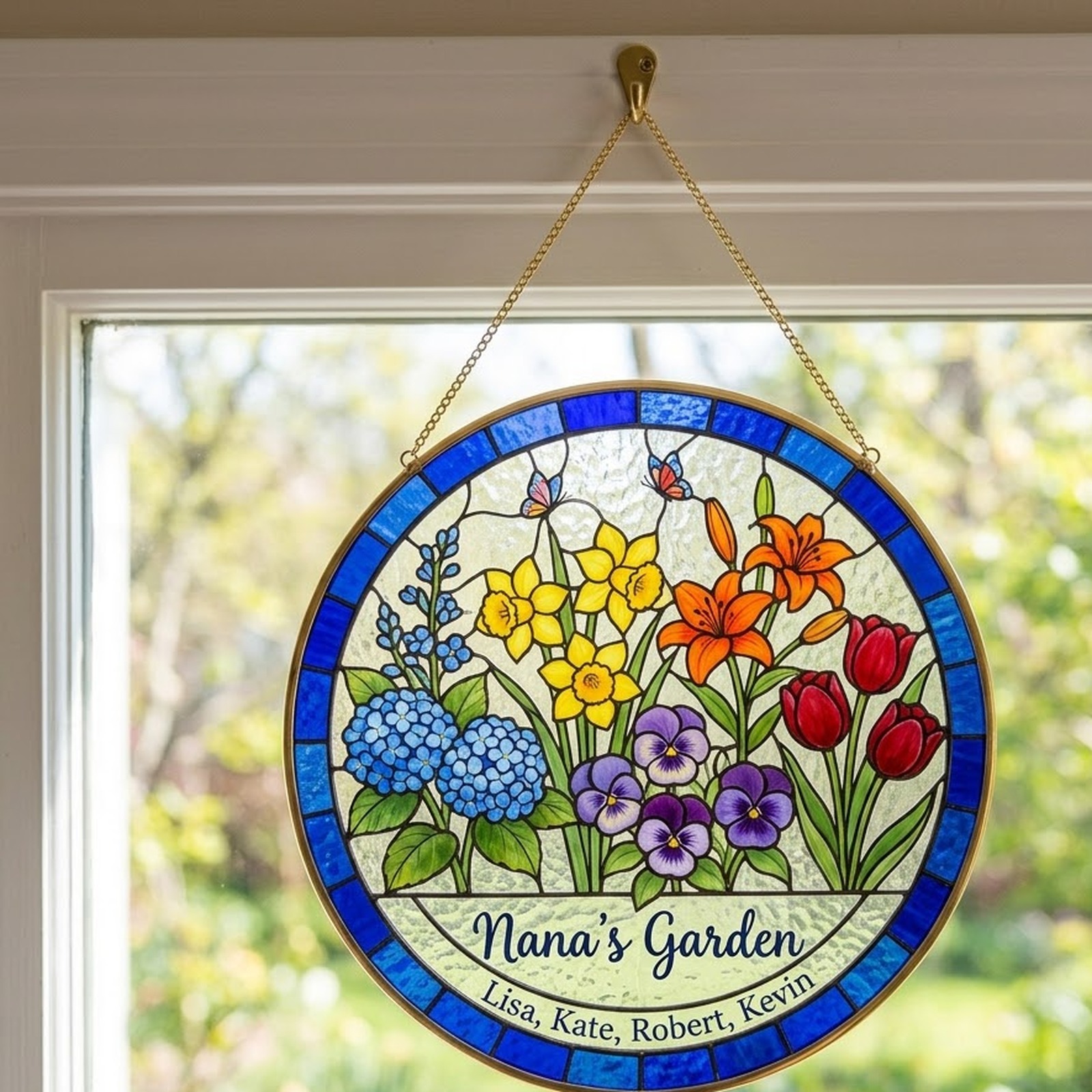 Nana's Garden birth flower suncatcher hanging on a gold chain in a sunny window