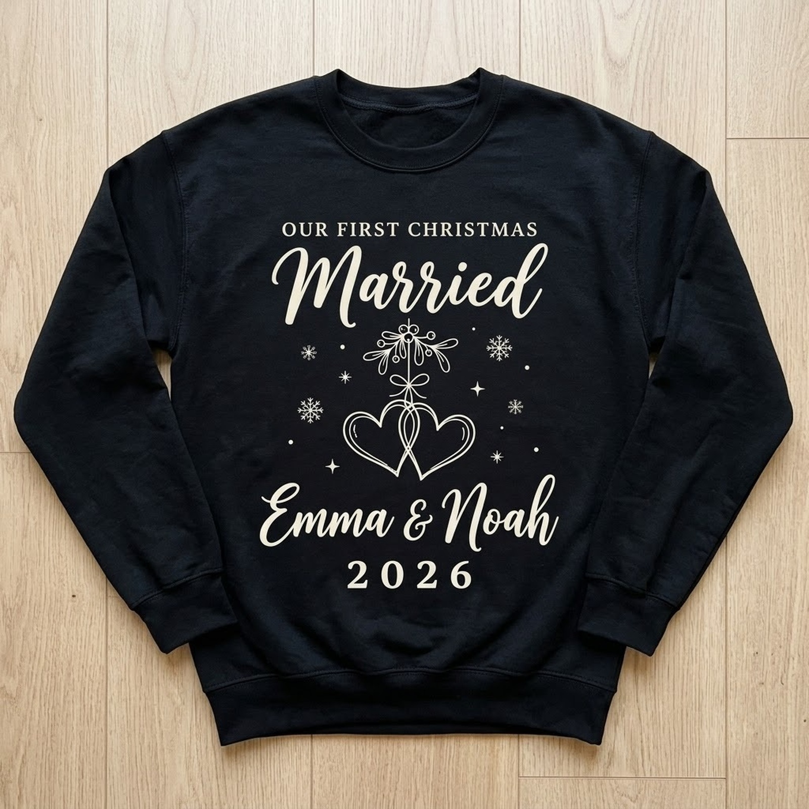 First christmas married sweatshirt in black laid flat, names Emma & Noah 2026